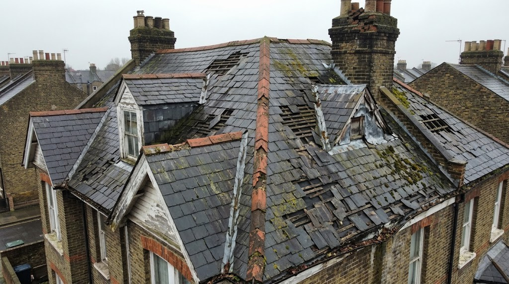 Before photo of a damaged moss-covered roof on a Hammersmith property prior to restoration